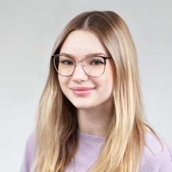 A blonde woman in a purple blouse with glasses smiling